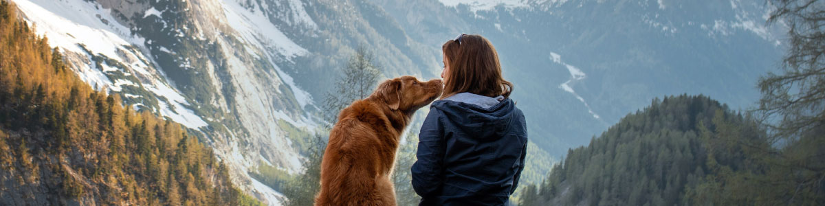 Woman sitting on mountain with her golden retriever.
