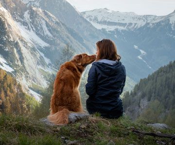 Woman sitting on mountain with her golden retriever